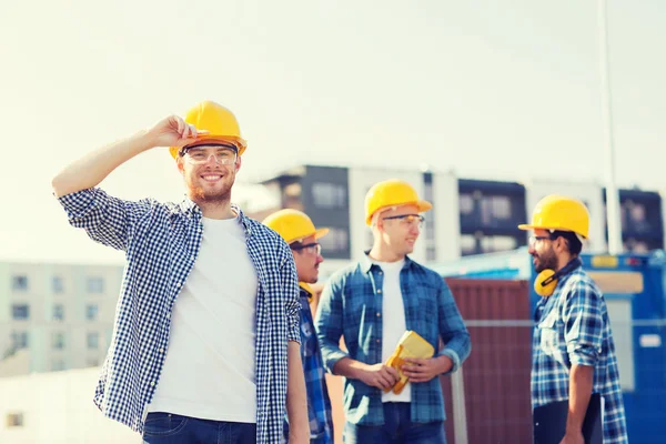 Grupp av leende byggare i hardhats utomhus — Stockfoto