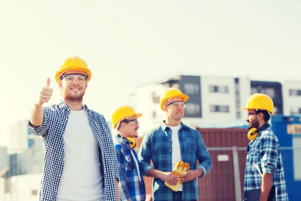 Grupa budowniczych uśmiechający się w hardhats na zewnątrz — Zdjęcie stockowe