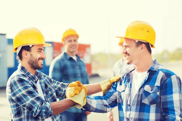 Grupa budowniczych uśmiechający się w hardhats na zewnątrz — Zdjęcie stockowe