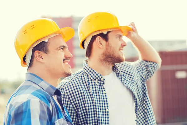 Groep van lachende bouwers in hardhats in openlucht — Stockfoto