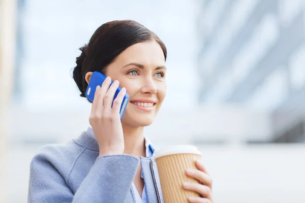 Smiling woman with coffee calling on smartphone — Stock Photo, Image