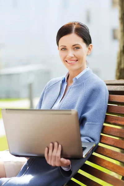 Smiling business woman with laptop in city — Stock Photo, Image