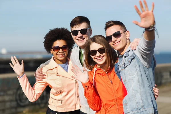 Happy dospívající přátelé v odstínech mává rukama — Stock fotografie