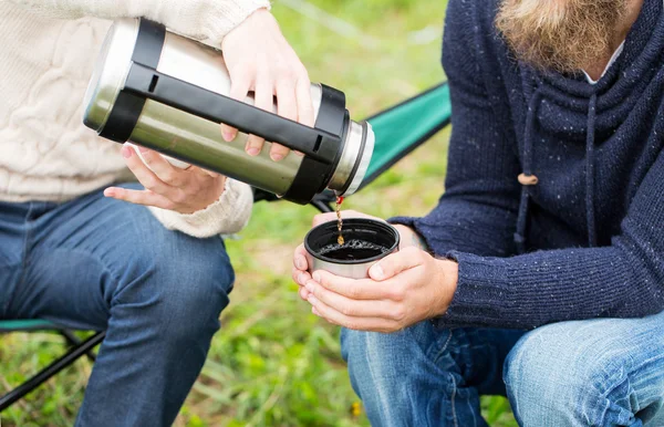 Nahaufnahme von Wanderern, die Tee von der Thermoskanne in die Tasse gießen — Stockfoto