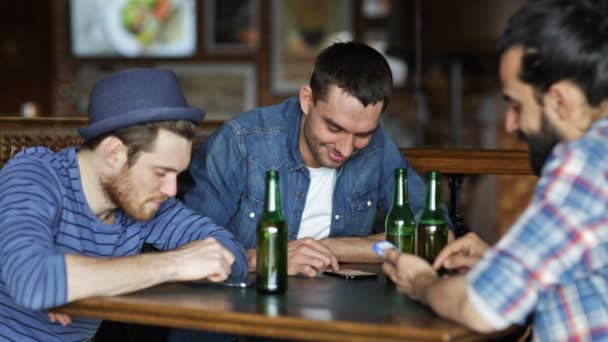 Друзья со смартфонами пьют пиво в баре — стоковое видео