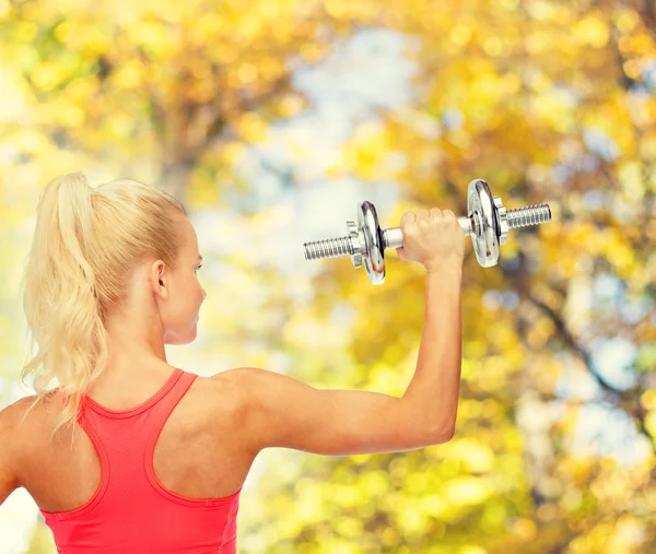 Sportieve vrouw met zware stalen dumbbell van terug — Stockfoto