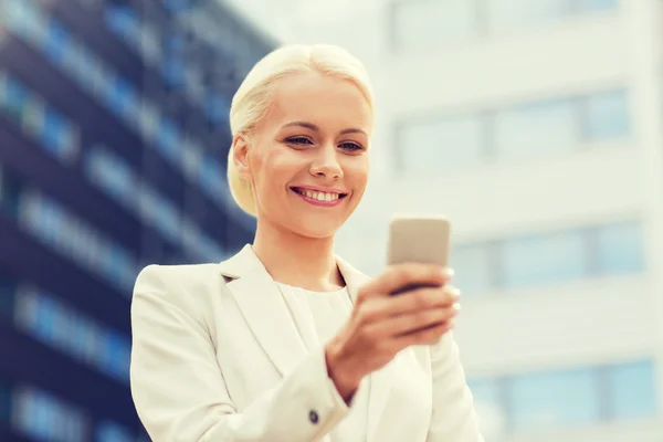 Smiling businesswoman with smartphone outdoors — Stock Photo, Image