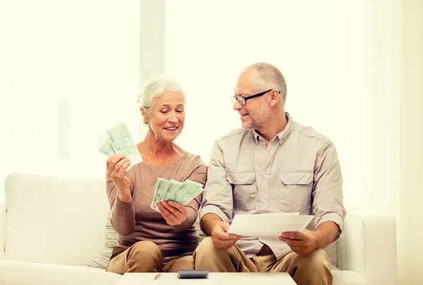 Senior paar met geld en rekenmachine thuis — Stockfoto