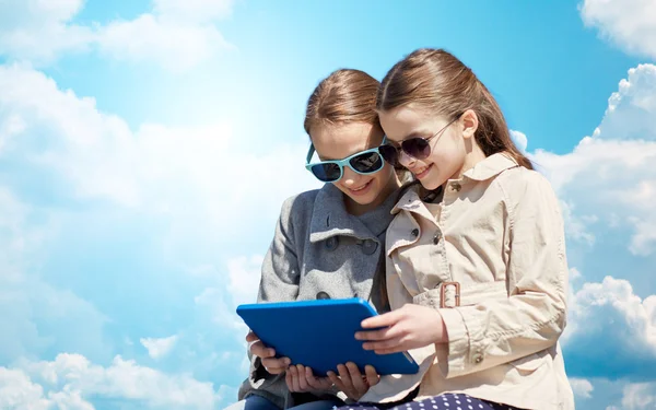 Happy girls with tablet pc computer over blue sky — Zdjęcie stockowe