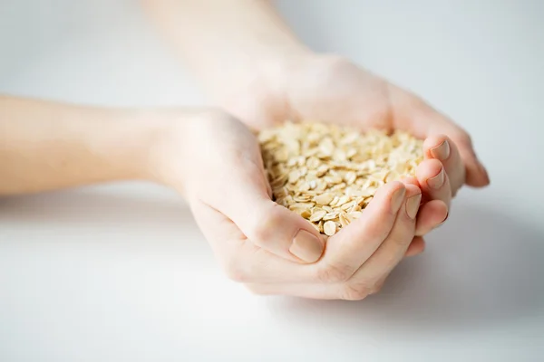 Primer plano de las manos de la mujer sosteniendo copos de avena — Foto de Stock