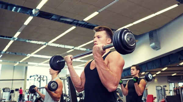 Grupp män flexar muskler med skivstång i gym — Stockfoto