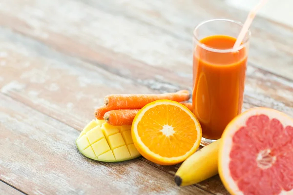 Närbild av färsk juice glas och frukter på bord — Stockfoto