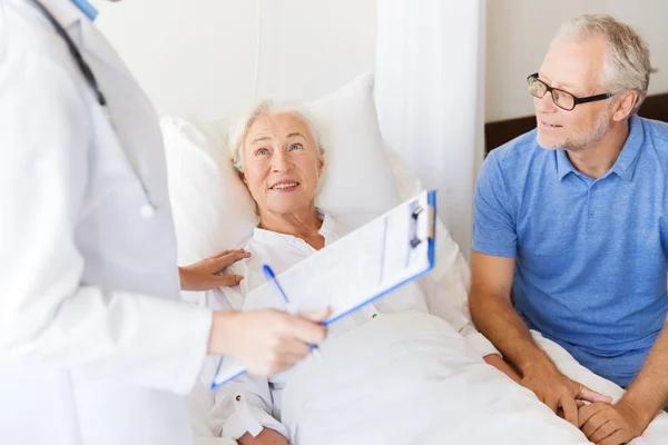 Seniorin und Arzt mit Klemmbrett im Krankenhaus — Stockfoto