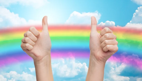 Hands showing thumbs up over rainbow in blue sky — Stok fotoğraf