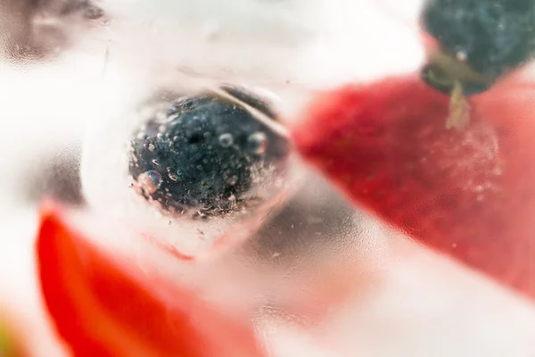 Primer plano de agua de frutas con cubitos de hielo sobre vidrio — Foto de Stock