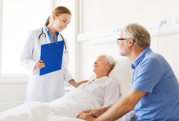 Senior woman and doctor with clipboard at hospital — Stock Photo, Image