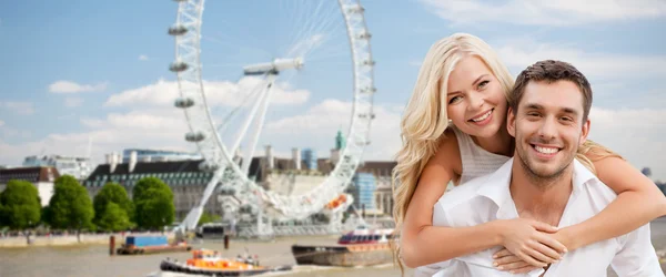 Happy couple hugging over london eye ferry wheel — Stockfoto
