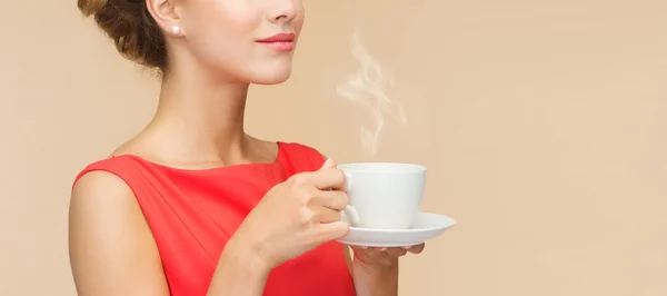 Lachende vrouw in rode jurk met kop koffie — Stockfoto