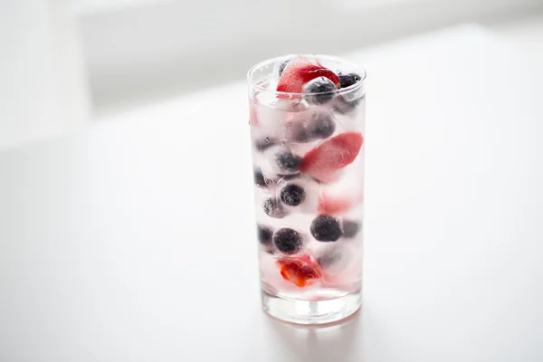 Close up of fruit water with ice cubes in glass — Stockfoto