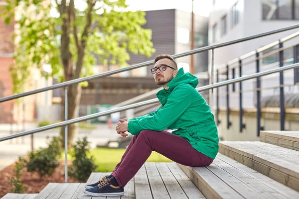 Heureux jeune homme hipster assis sur les escaliers en ville — Photo