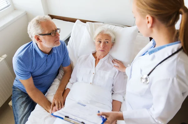 Senior woman and doctor with clipboard at hospital — Stock Photo, Image