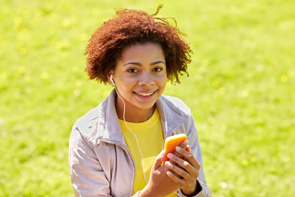 Happy afrikansk kvinna med smartphone och hörlurar — Stockfoto