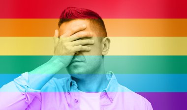 gay covering his face by hand over rainbow flag clipart