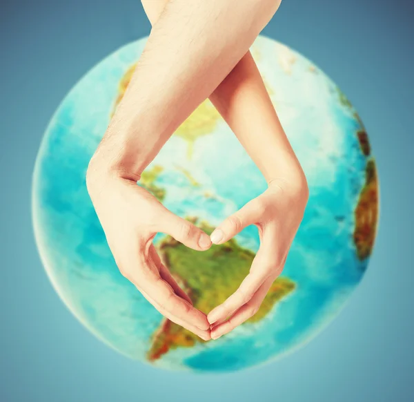 Human hands showing heart shape over earth globe — Stock Photo, Image