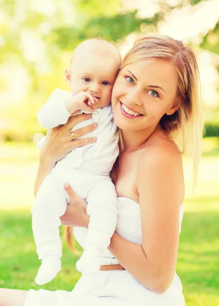 Счастливая мать с маленьким ребенком, сидящим на одеяле — стоковое фото