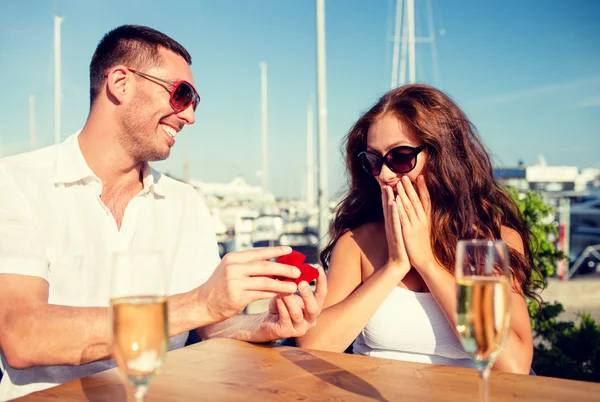 Lachende paar met champagne en gift bij café — Stockfoto