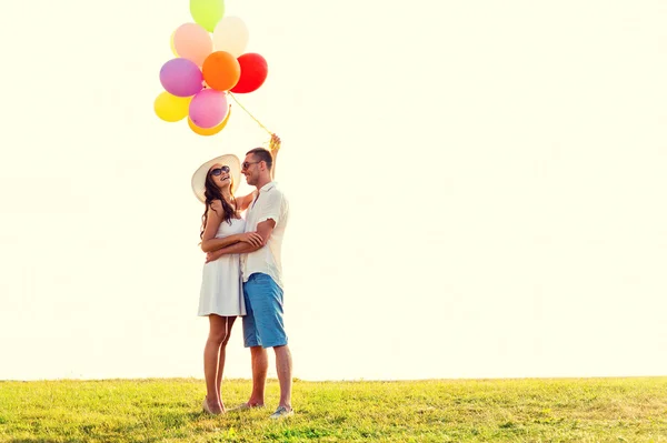 Smiling couple with air balloons outdoors — Stock Photo, Image