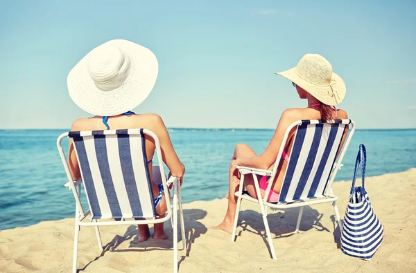 Mujeres felices tomando el sol en salones en la playa — Foto de Stock