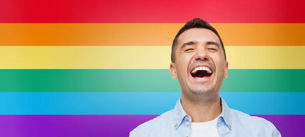Laughing man over rainbow flag stripes background — ストック写真