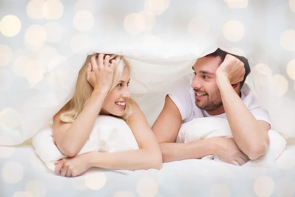 Happy couple lying in bed and talking at home — Stock Photo, Image