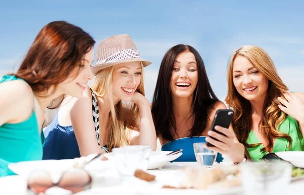 Chicas mirando el teléfono inteligente en la cafetería en la playa —  Fotos de Stock