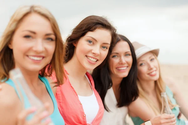 Ragazze sorridenti con bevande sulla spiaggia — Foto Stock