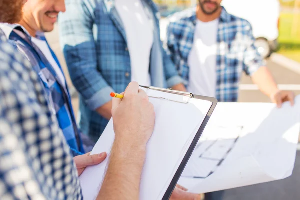 Primer plano de los constructores con portapapeles y plano —  Fotos de Stock