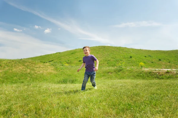 Niño feliz corriendo en el campo verde al aire libre — Foto de Stock