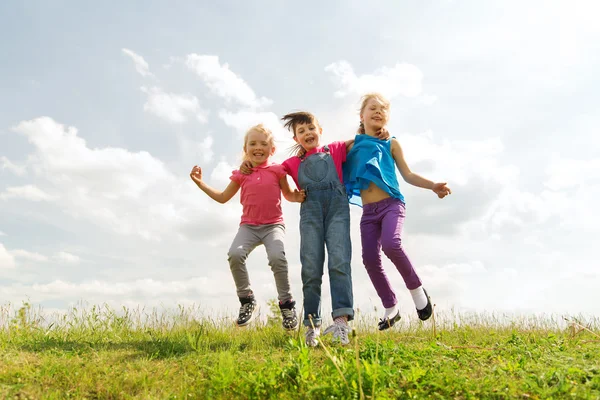 Grupo de niños felices saltando alto en el campo verde —  Fotos de Stock