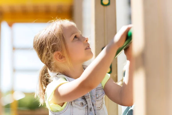 Fröhliches kleines Mädchen klettert auf Kinderspielplatz lizenzfreie Stockfotos