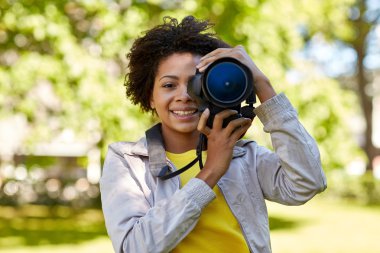 happy african woman with digital camera in park clipart