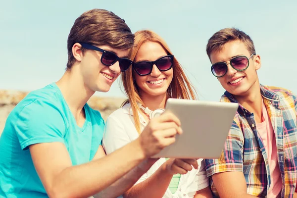 Группа улыбающихся друзей с планшетным ПК на открытом воздухе — стоковое фото