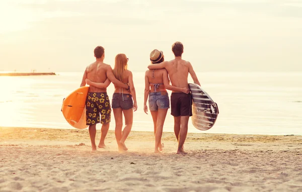 Amici sorridenti in occhiali da sole con surfisti sulla spiaggia — Foto Stock