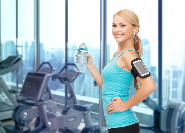 Mujer deportiva sonriente con teléfono inteligente y auriculares —  Fotos de Stock