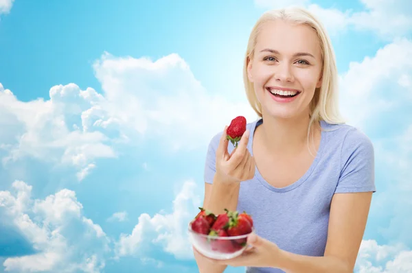 Happy woman eating strawberry over sky — Stok fotoğraf