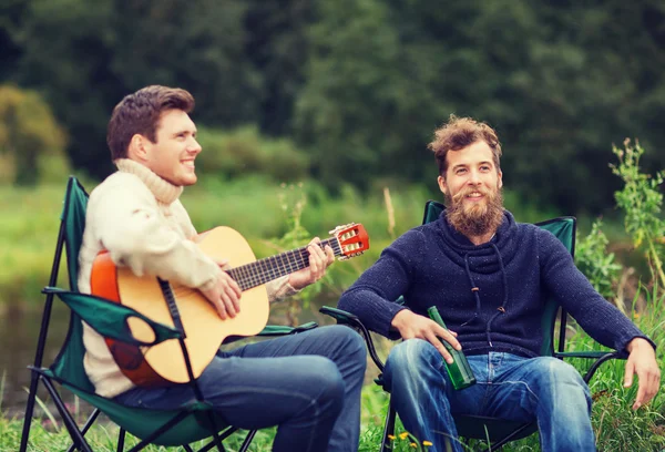 Turistas sorridentes tocando guitarra no acampamento — Fotografia de Stock