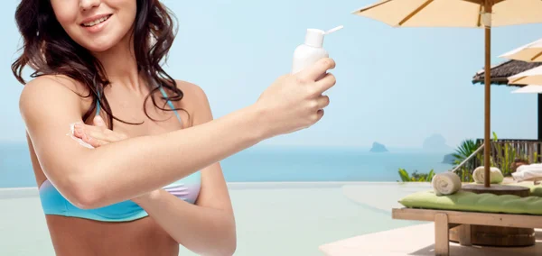 Щаслива молода жінка в купальнику застосовує сонцезахисний крем — стокове фото
