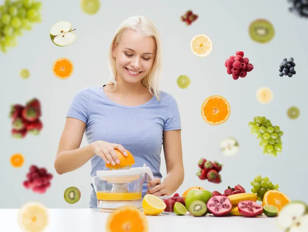 Mulher sorrindo espremendo suco de frutas em casa — Fotografia de Stock