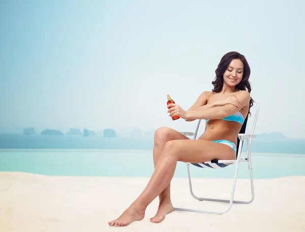 Happy woman sunbathing and applying sunscreen — ストック写真