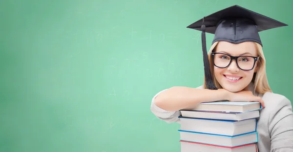 Студент в траншеї шапки з книгами над зеленим — стокове фото
